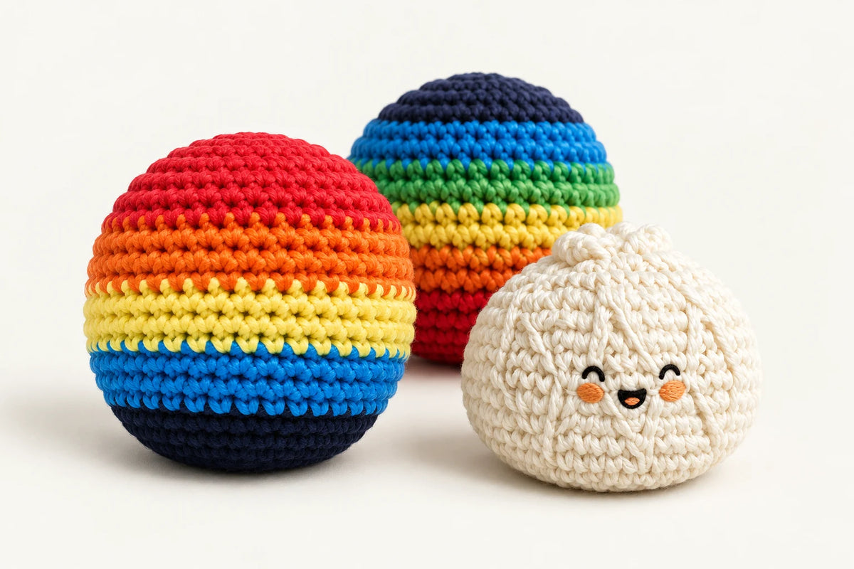 Two colorful crochet footbags beside a cream knitted bun hacky sack