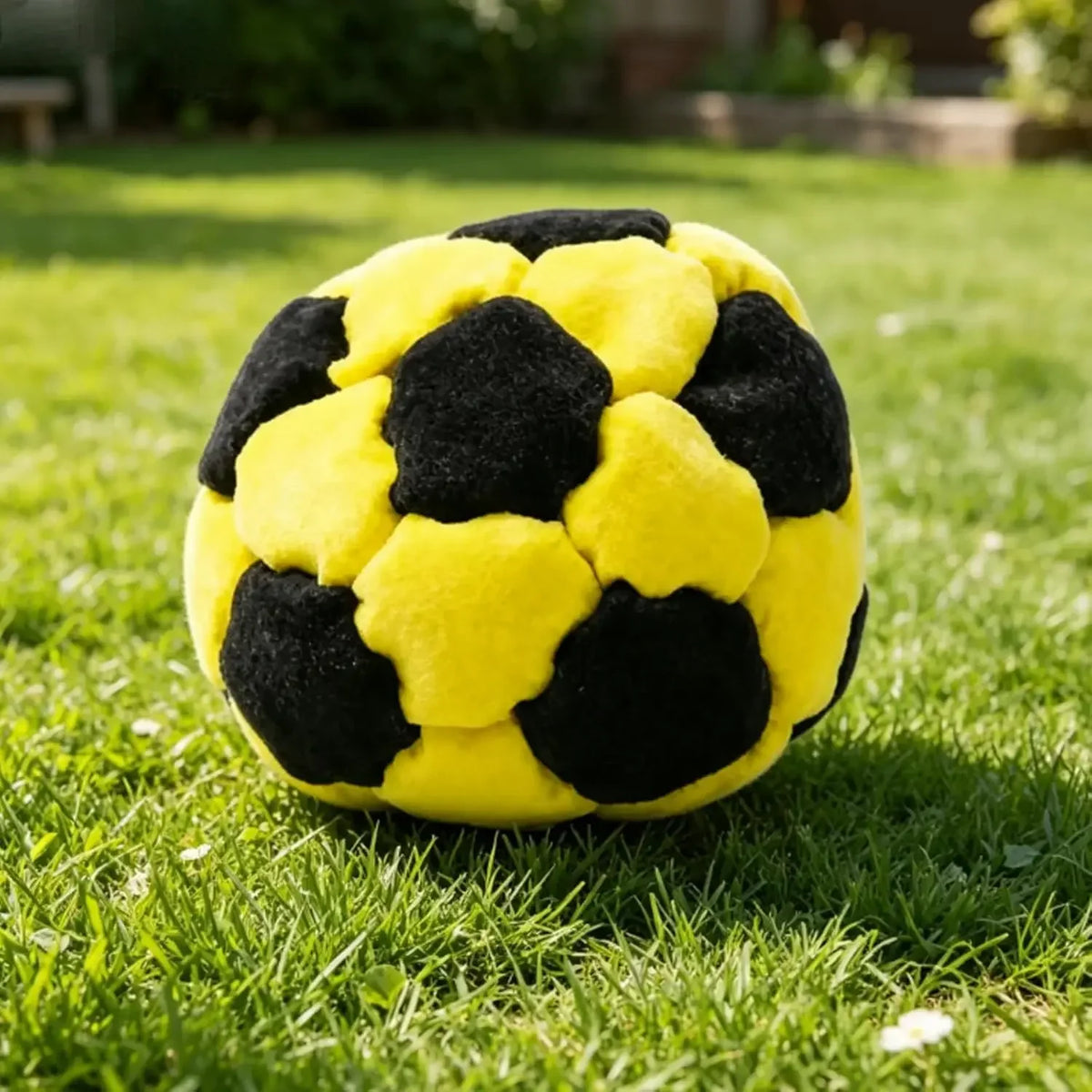 Yellow and black soft soccer footbag on grass