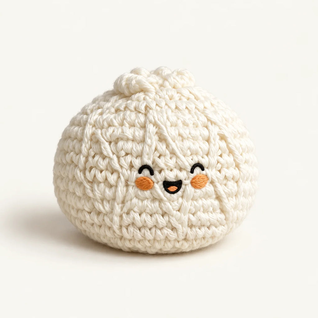 Single cream knitted bun footbag with embroidered smiling face on an ivory background